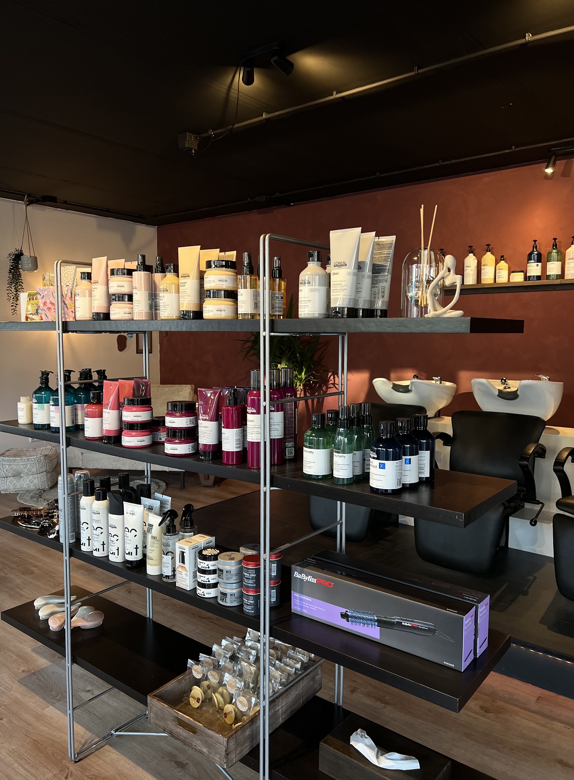 Schappen met haarproducten naast de wasbakken in de salon
