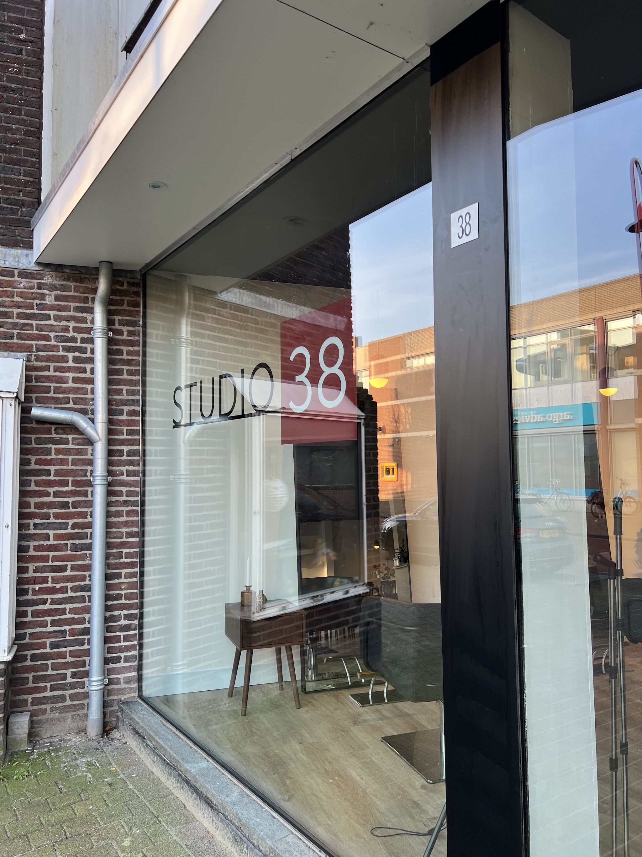 De winkelpui van Studio 38 met de belettering op het raam en huisnummer 38