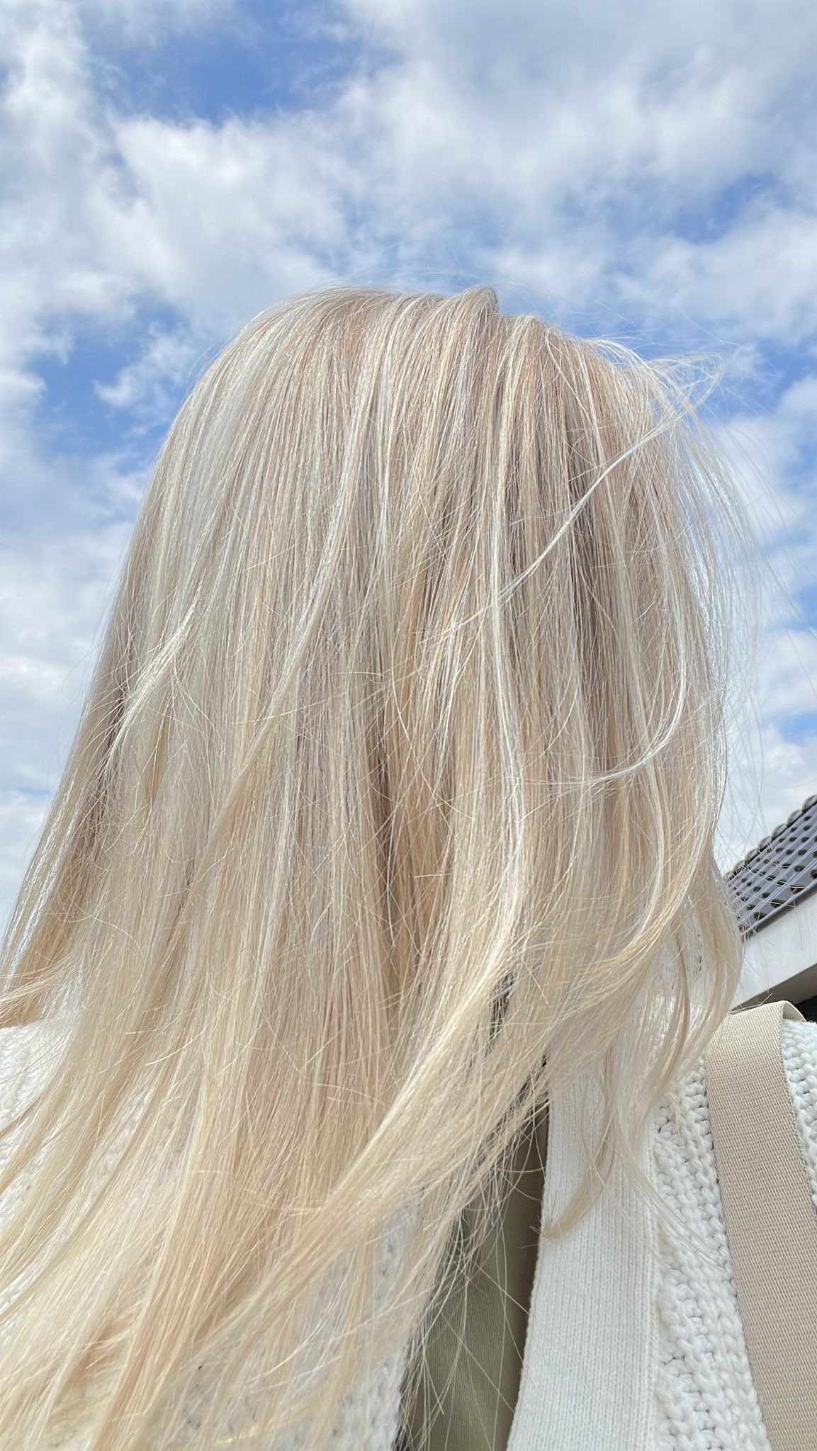 Lang blond haar met een frisse kleur, van achteren gezien tegen een blauwe lucht